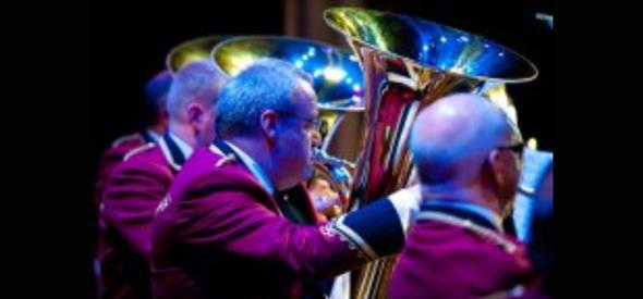 Group of men playing large brass instrument in spotlight