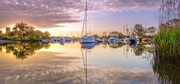 Christchurch Quay docked with sailboats and Priory in the distance.