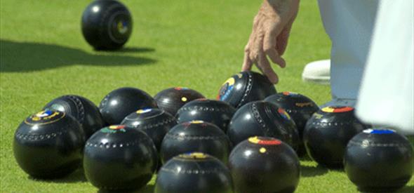 man reaching down to a bowls ball.