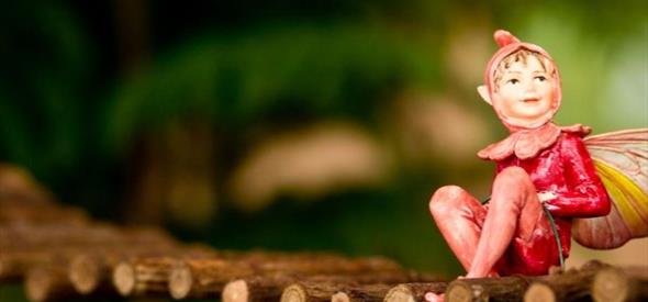 Fairy sitting on a small fairy bridge, gazing into the distance.