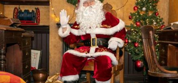 santa sat on a chair with a decorated christmas tree in the background