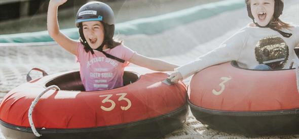 Two girls going down the dry ski slope together on their ringos