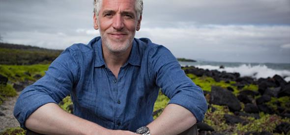 Man sitting outside with dramatic landscape behind him