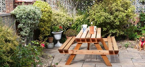 Cosy garden with wooden seating area surrounded with plants and trees