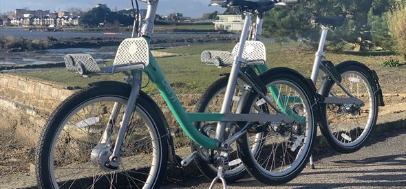 Beryl bikes outside on the street, with view of the sea in the background