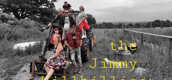 Four men and three women posed on a digger in a field. Background is black and white but the figures are in colour