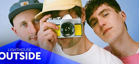 Three young men pointing a film camera at the viewer with blue triangle overlaid that reads LIGHTHOUSE OUTSIDE