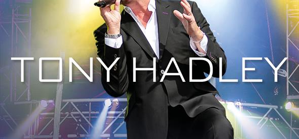 Tony Hadley in a suit singing into a microphone on stage