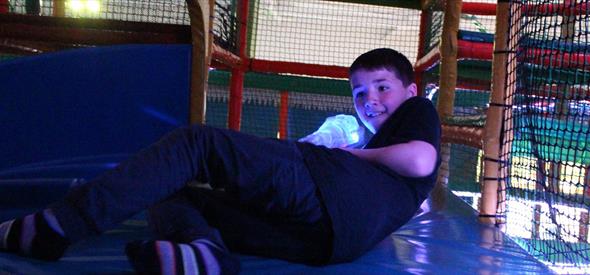 Boy climbing through a colourful soft play area