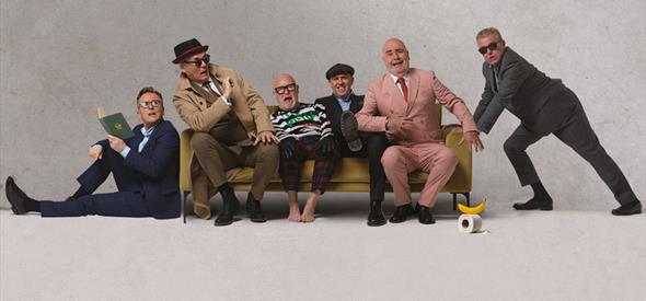 The band Madness sat on a sofa posing for the camera