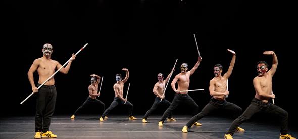 Seven dancers on stage striking a pose with poles