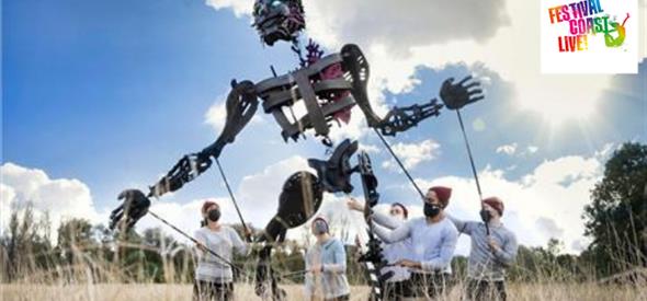 A giant black puppet standing in a wheat field operating by 5 puppeteers in white t-shirts