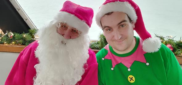 Santa with an elf next to him on a boat