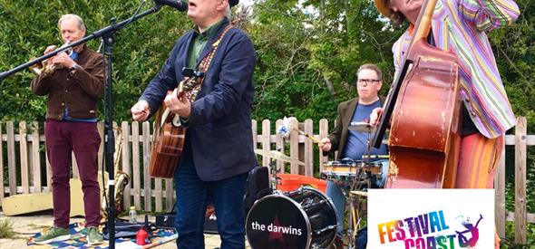 4 piece band with double bass in front of fence & trees