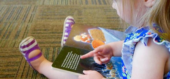 A young girl sitting on the floor reading a book