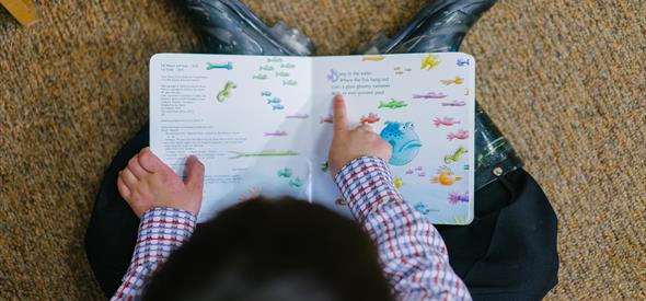 A young child reading a story book about fish.