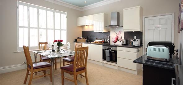 Kitchen with appliances and glass table and wooden chairs