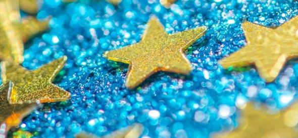 Golden stars laying on a shiny blue background.