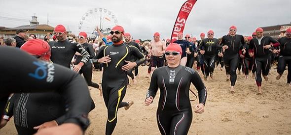 Lady in swim gear running with crowd down the beach