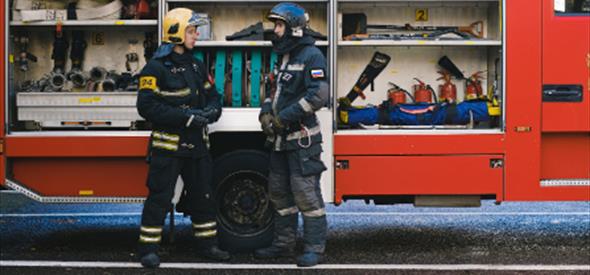 Two fireman talk outside their truck