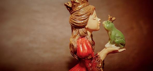 A princess preparing to kiss a frog held in her hands