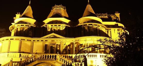 Exterior of Russell-Cotes illuminated at night by orange light