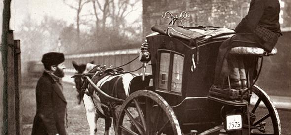 old time photograph of one man on a horse and buggy and another man standing in the street