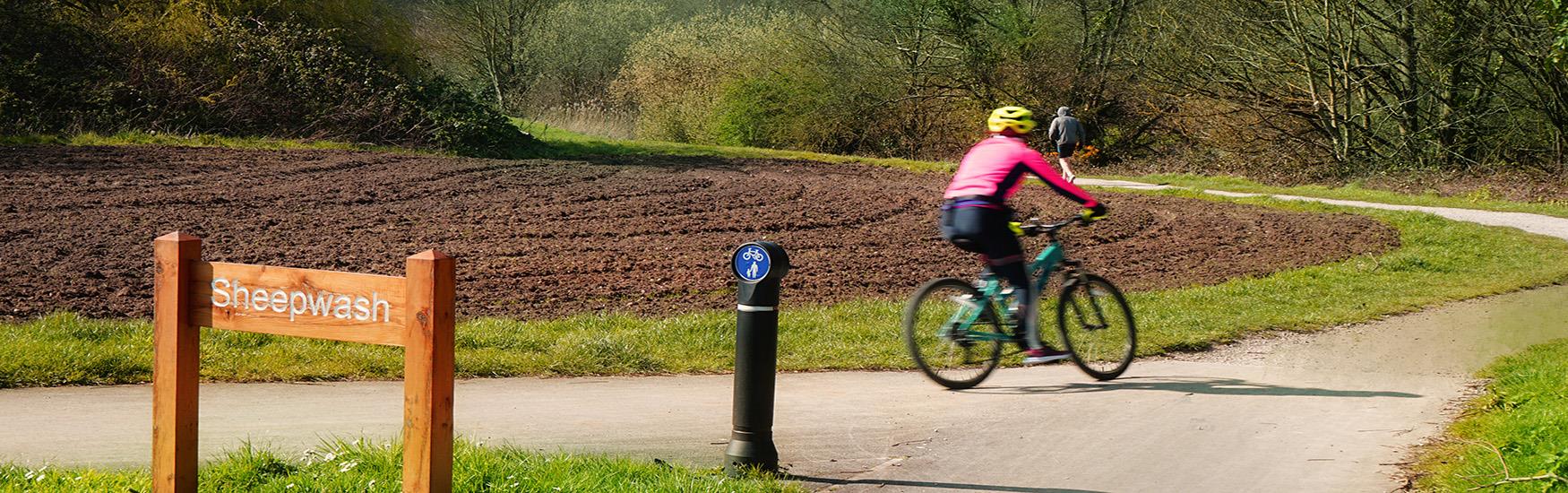 A woman keeping fit on her bike whilst a man jogs in front around a Chrischuch sports route