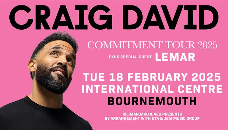 Craig David in a black top looking up and smiling