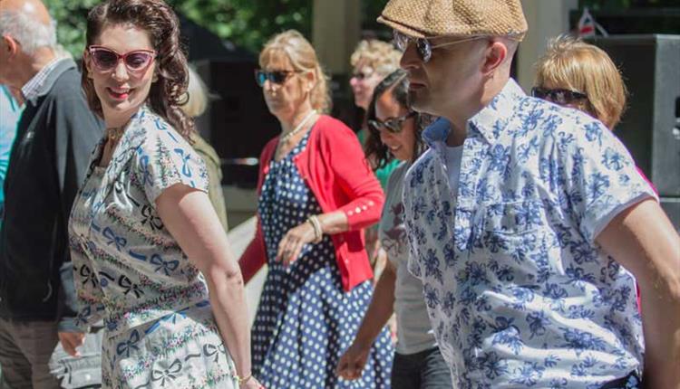 A close-up group of people with hands behind their backs dancing