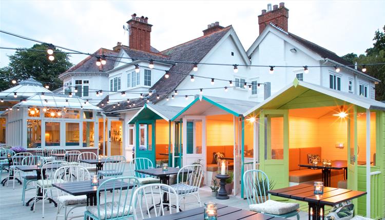 Outdoor seating area of the oaks with fairy lights and beach hut booths.