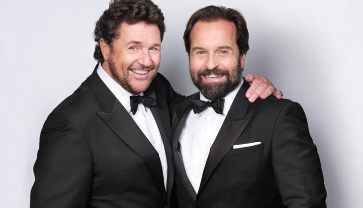 Two men in black and white suits on a plain background