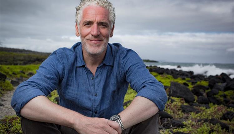 Man sitting outside with dramatic landscape behind him