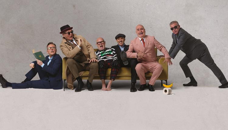 The band Madness sat on a sofa posing for the camera