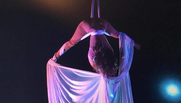 Woman hanging down from the ceiling in white linen wrapped around her