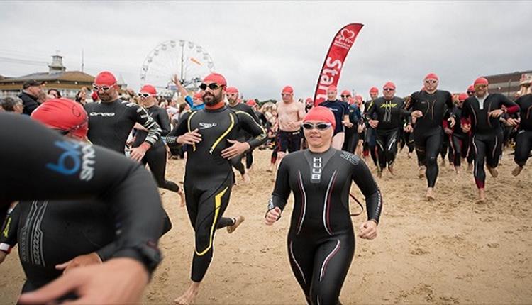 Lady in swim gear running with crowd down the beach