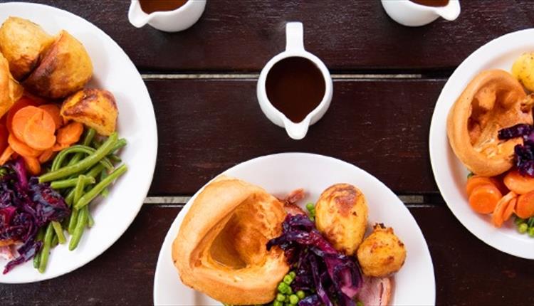 plates of roast dinner on a picnic bench.