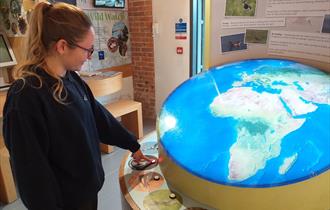 Lady pressing button to illuminate globe