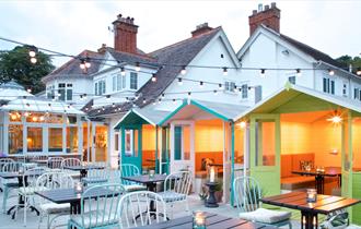 Outdoor seating area of the oaks with fairy lights and beach hut booths.