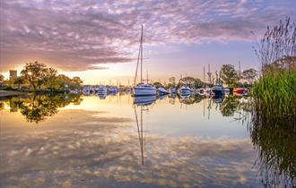 Christchurch Quay docked with sailboats and Priory in the distance.
