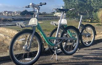 Beryl bikes outside on the street, with view of the sea in the background
