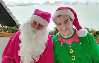 Santa and a elf smiling at the camera