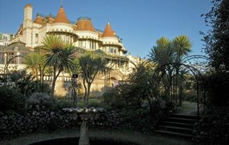 The Russell-Cotes Art Gallery & Museum Victorian villa in the background set against blue sky, with a fountain and trees in the foreground