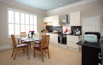 Kitchen with appliances and glass table and wooden chairs