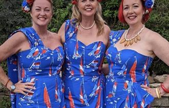 3 women pose for the cameria in their union jack coloured outfits