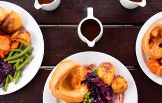 plates of roast dinner on a picnic bench.