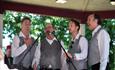 Four men standing outside with microphone singing