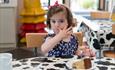 little girl eating cake at Farmer Palmer's Farm Park
