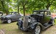 Black and grey vintage cars underneath the trees