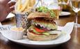 Tasty stacked burger and fries sat on table ready to be eaten